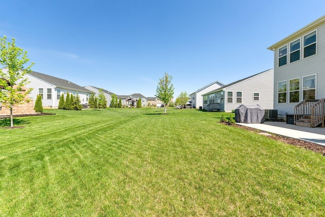 view of yard featuring a residential view, a patio, and central AC