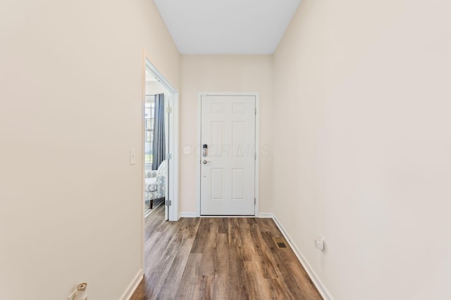 doorway to outside featuring baseboards, dark wood-style flooring, and visible vents