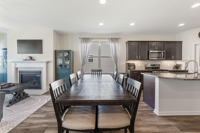 dining area featuring a fireplace, recessed lighting, and dark wood-type flooring
