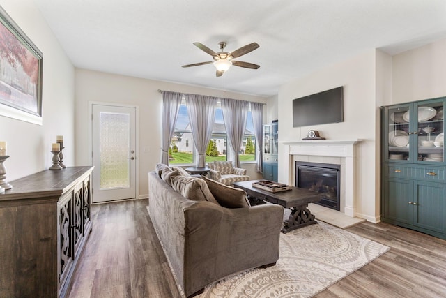 living room with baseboards, a ceiling fan, wood finished floors, and a fireplace