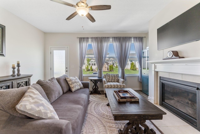 living room featuring light tile patterned floors, baseboards, ceiling fan, and a fireplace
