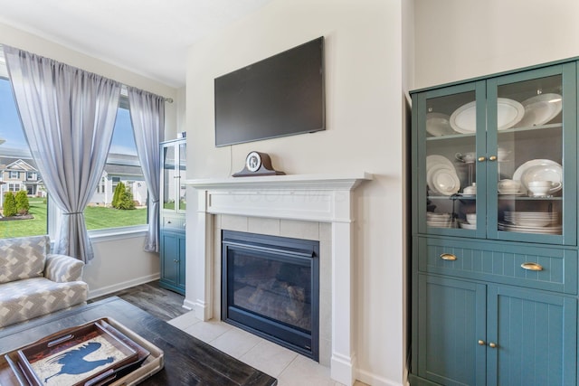living room with baseboards, light wood finished floors, and a tile fireplace