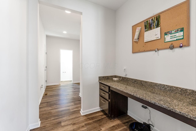 unfurnished office featuring built in study area, recessed lighting, dark wood finished floors, and baseboards