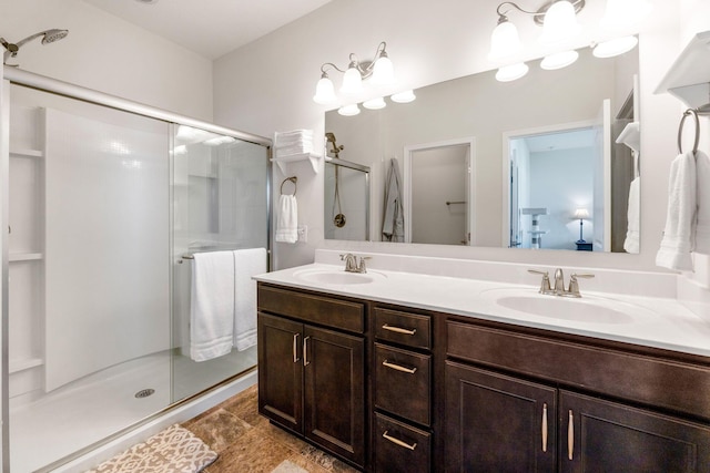 bathroom with a sink, a shower stall, and double vanity