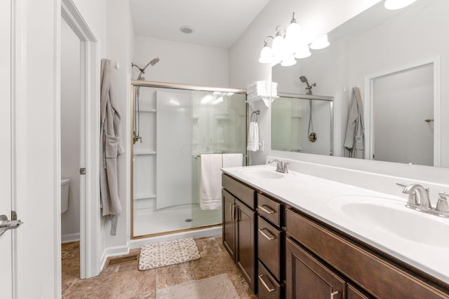 full bathroom with a sink, stone finish floor, a shower stall, and double vanity