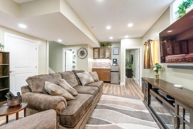 living area featuring recessed lighting, light wood-style flooring, baseboards, and indoor bar