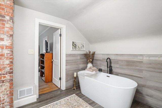 8056 Summit Rd SW, Pataskala, OH 43062 - bathroom featuring visible vents, a freestanding tub, wainscoting, wood finished floors, and vaulted ceiling