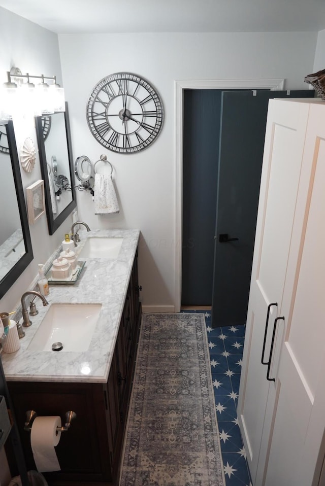 full bathroom featuring baseboards, double vanity, and a sink