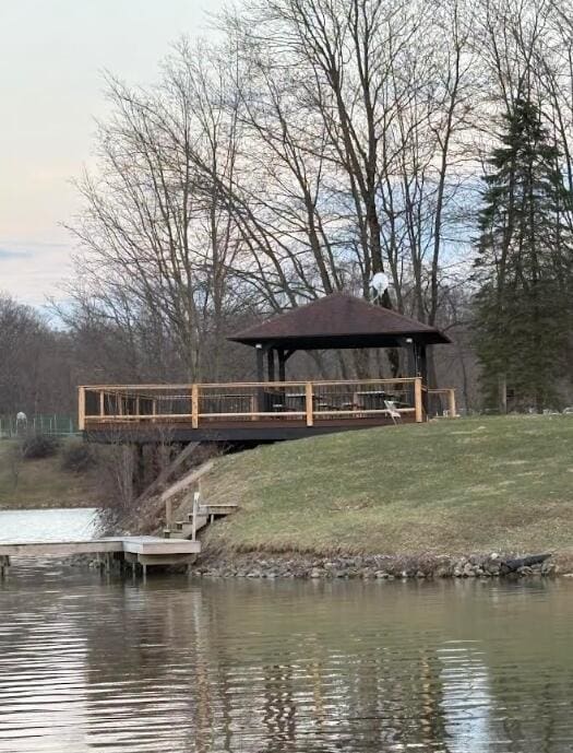 view of dock featuring a water view, a gazebo, and a yard