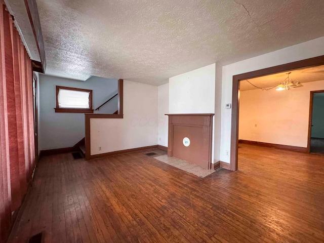unfurnished living room with a textured ceiling, baseboards, a chandelier, stairway, and hardwood / wood-style flooring
