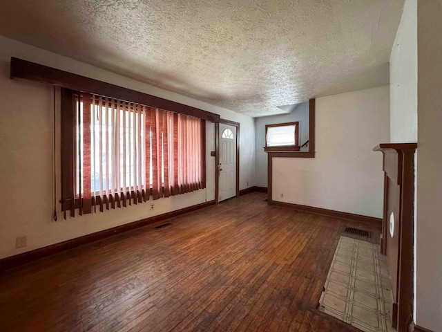 unfurnished living room with hardwood / wood-style floors, baseboards, visible vents, and a textured ceiling