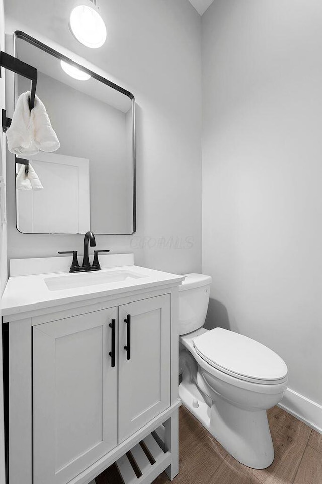 bathroom with wood finished floors, toilet, and vanity