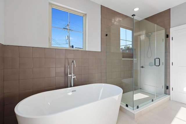 full bath with tile walls, a freestanding tub, recessed lighting, and a shower stall