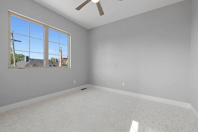 empty room with carpet floors, baseboards, visible vents, and ceiling fan