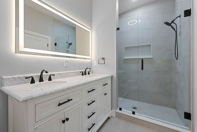 bathroom featuring double vanity, a sink, a stall shower, and tile patterned floors