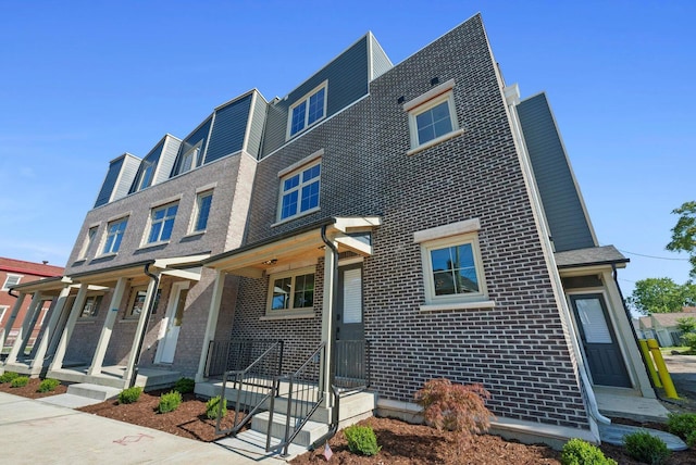 multi unit property with brick siding and a porch