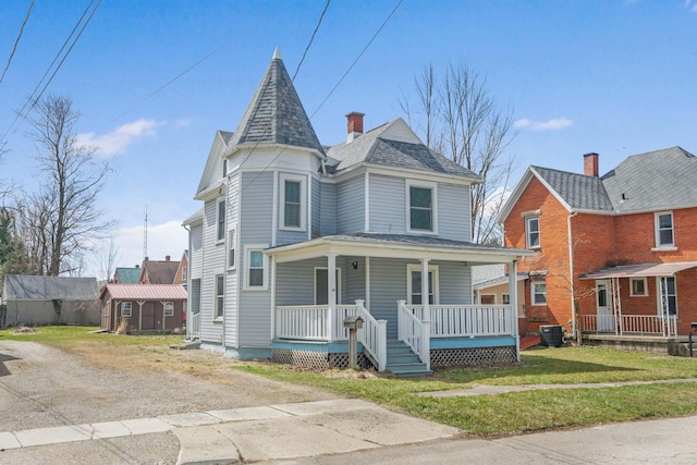 victorian-style house featuring central air condition unit, a front lawn, a porch, and roof with shingles