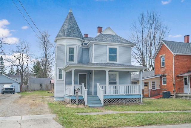victorian house with a front yard, covered porch, a chimney, a shingled roof, and central AC unit