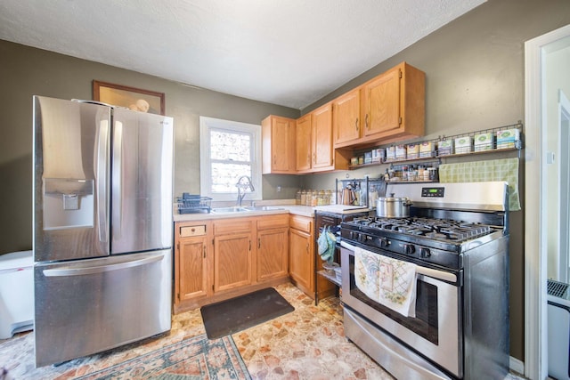 kitchen with a textured ceiling, light countertops, a sink, and appliances with stainless steel finishes