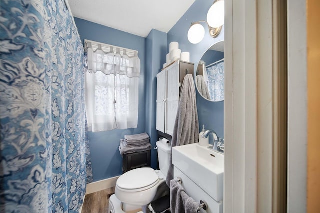bathroom with toilet, curtained shower, vanity, wood finished floors, and baseboards