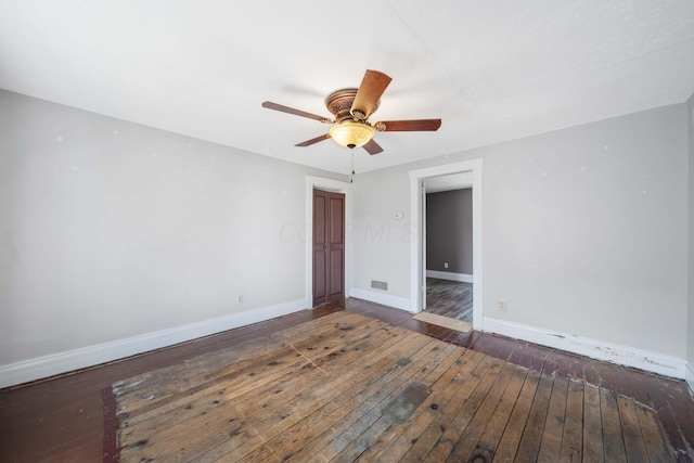 empty room featuring baseboards, visible vents, a ceiling fan, and wood-type flooring