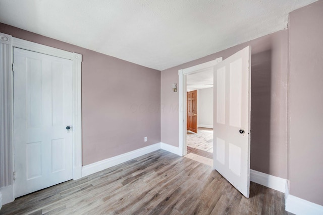 spare room featuring baseboards and wood finished floors