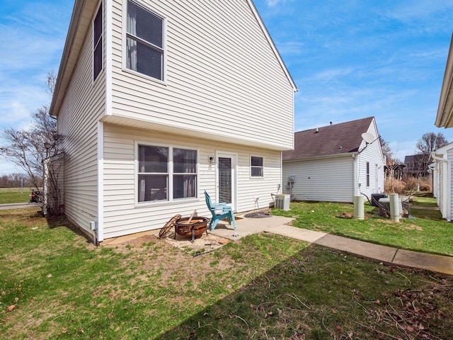 back of property with a fire pit, central AC unit, a patio area, and a lawn