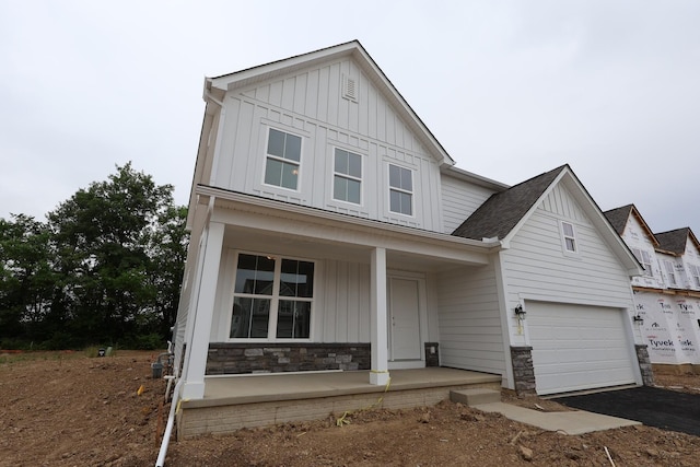 222 Silver Pine Ln, Lewis Center, OH 43035 - view of front of property featuring board and batten siding, a porch, stone siding, and driveway