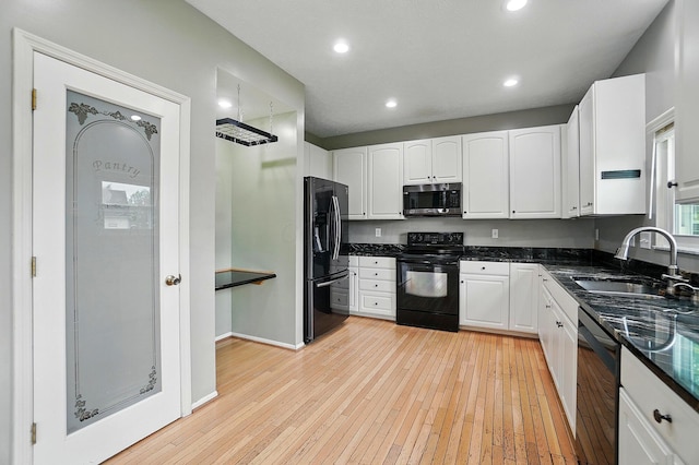 kitchen featuring black appliances, a sink, white cabinets, light wood-type flooring, and recessed lighting