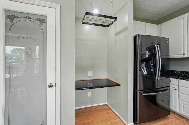 kitchen featuring fridge with ice dispenser, light wood-style floors, and white cabinets