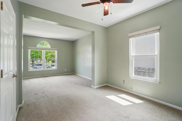 carpeted empty room with a ceiling fan and baseboards