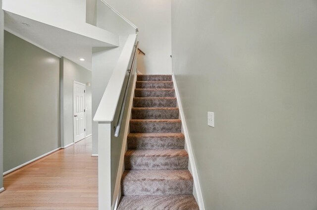 stairway with wood finished floors, recessed lighting, and baseboards