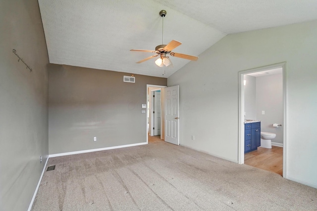 unfurnished bedroom with carpet floors, vaulted ceiling, ensuite bath, and baseboards