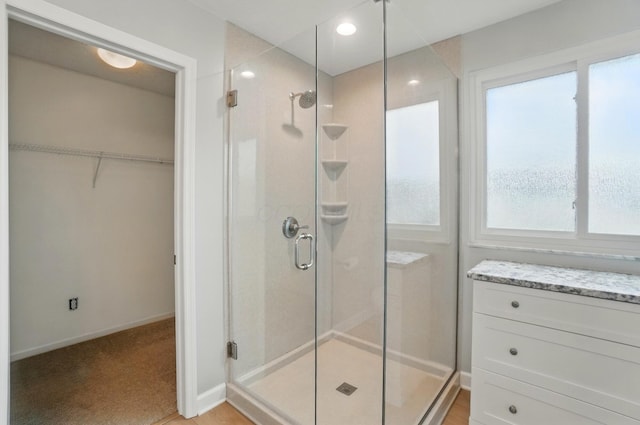 full bath with a stall shower, healthy amount of natural light, a spacious closet, and baseboards