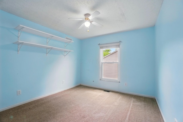 empty room featuring carpet floors, ceiling fan, a textured ceiling, and baseboards