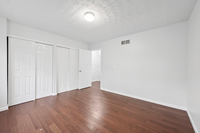 5692 Great Hall Ct, Columbus, OH 43231 - unfurnished bedroom featuring multiple closets, baseboards, wood finished floors, and a textured ceiling