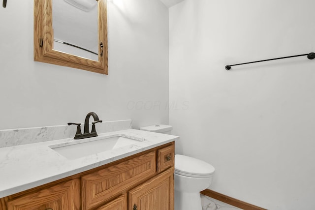 half bathroom with toilet, marble finish floor, vanity, and baseboards