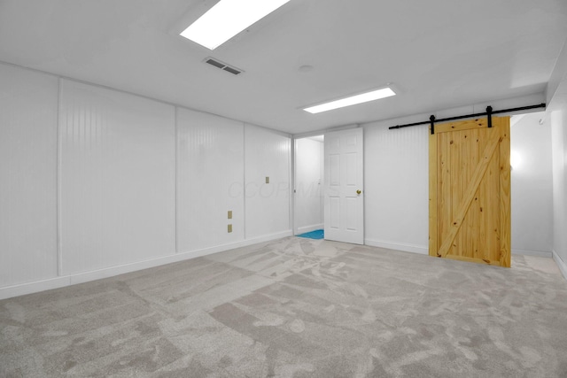 finished below grade area featuring a barn door, carpet, and visible vents