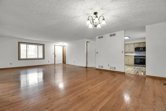 unfurnished living room with a chandelier, a textured ceiling, and visible vents