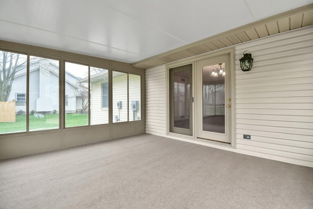 unfurnished sunroom with carpet flooring, a notable chandelier, and wooden walls
