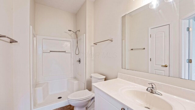 bathroom featuring toilet, a shower, and vanity