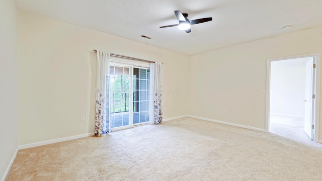 carpeted spare room featuring a ceiling fan, visible vents, and baseboards