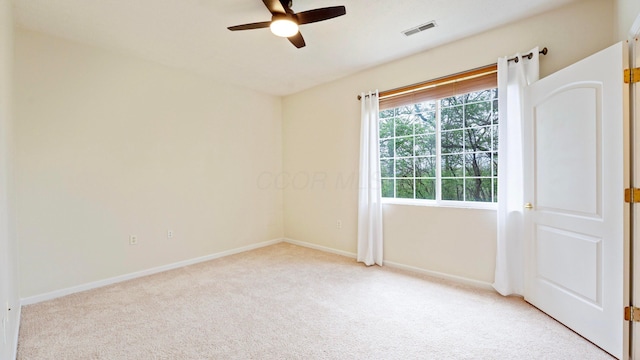 carpeted spare room featuring ceiling fan, visible vents, and baseboards