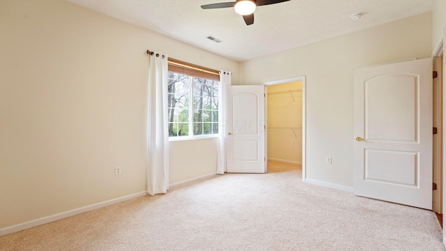 unfurnished bedroom featuring baseboards, visible vents, a walk in closet, and carpet flooring