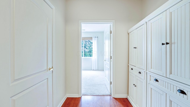 corridor with dark wood-style flooring and baseboards