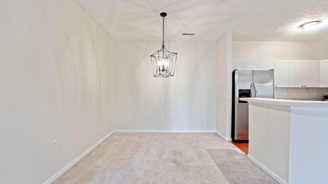 kitchen with white cabinets, light colored carpet, baseboards, stainless steel refrigerator with ice dispenser, and hanging light fixtures