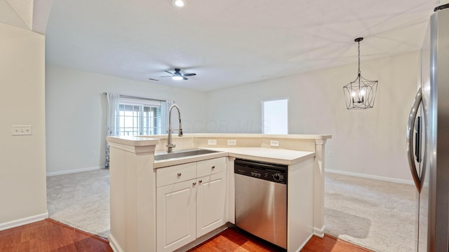 kitchen featuring stainless steel appliances, decorative light fixtures, light countertops, ceiling fan, and a sink
