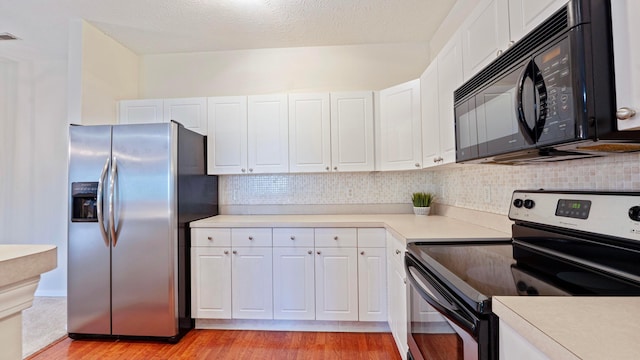 kitchen featuring tasteful backsplash, white cabinets, appliances with stainless steel finishes, light countertops, and light wood-type flooring