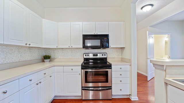 kitchen with white cabinetry, black microwave, stainless steel electric range, wood finished floors, and backsplash