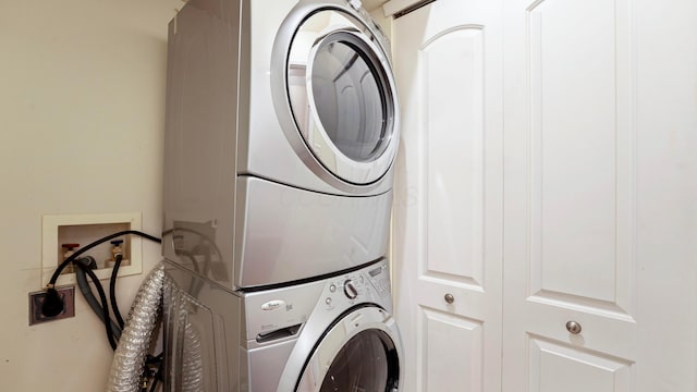 clothes washing area with stacked washing maching and dryer and laundry area